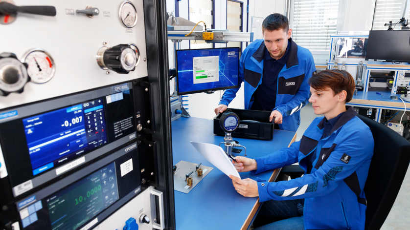 Employees in the calibration laboratory review documentation related to calibration certificates and evidence.