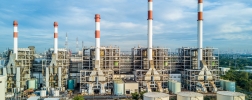 Wide shot of a power plant under a blue sky.